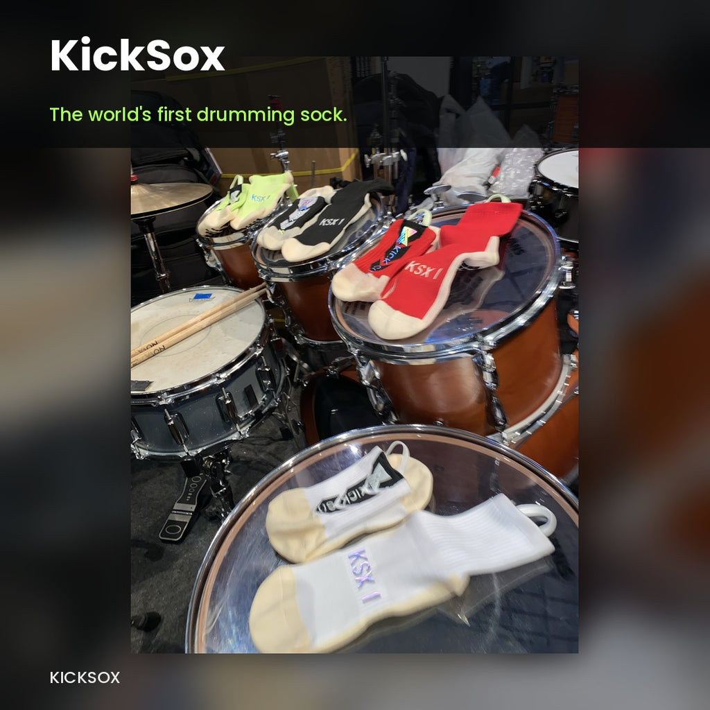 KickSox drumming socks in black, red, lime, and white laid out across an acoustic drum kit