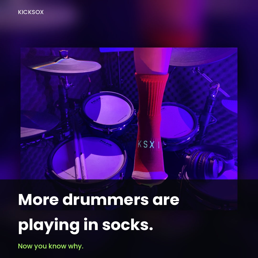 Drummer wearing a red KickSox sock at an electronic drum kit under stage lighting